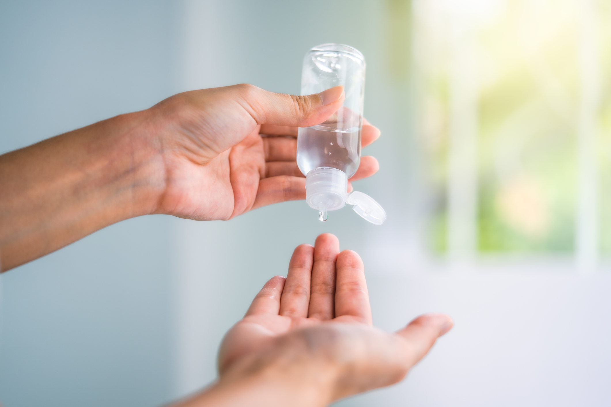 New normal life style after Covid-19 spread: Hand pour alcohol gel with transparent bottle to the other hand for sanitize bacteria and virus