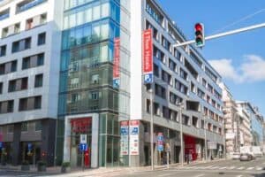 Modern hotel building with signage and parking in an urban setting.