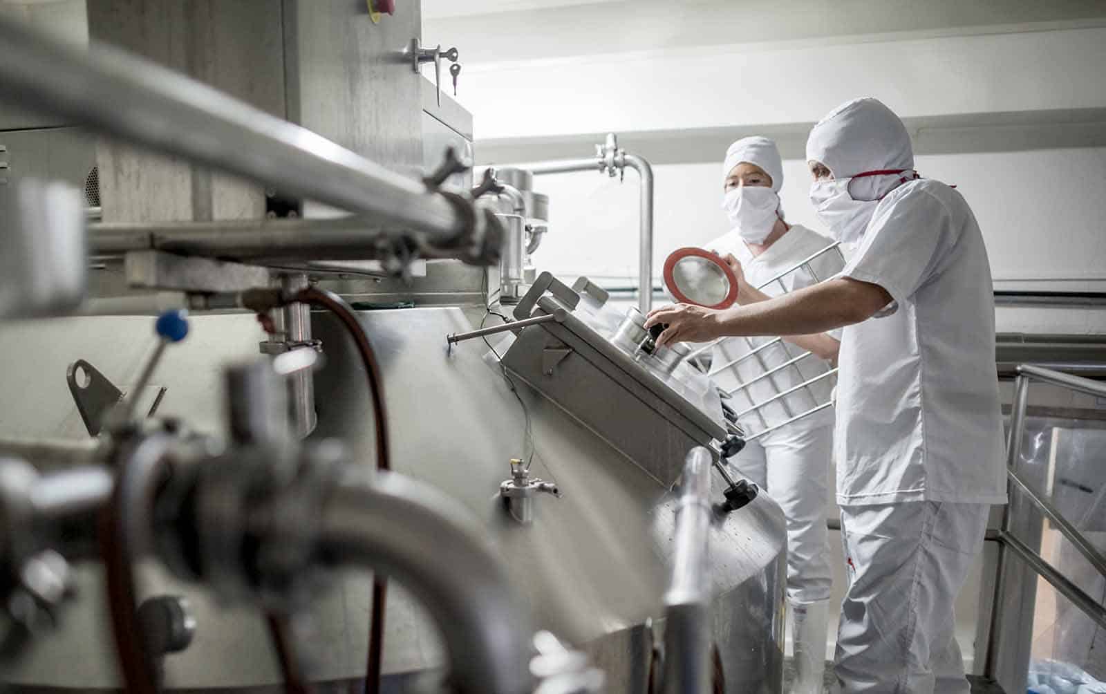 Workers inspecting detergent production line in a clean factory environment.